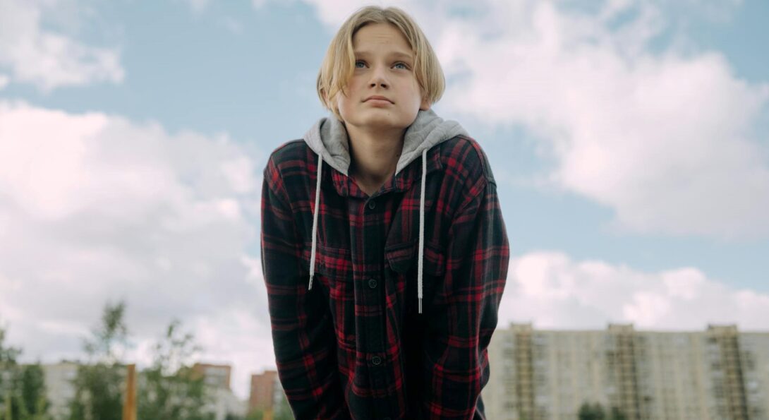 youth with plaid hoodie and hands in pocket