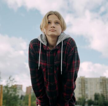 youth with plaid hoodie and hands in pocket
                  