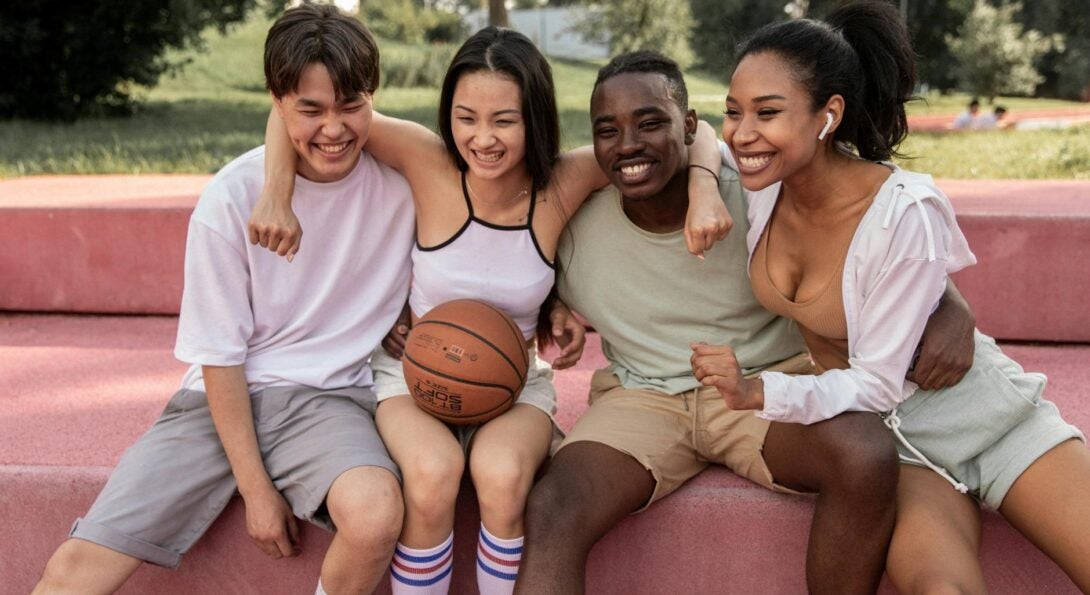 group of kids hugging one with a basketball