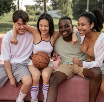 group of kids hugging one with a basketball
                  