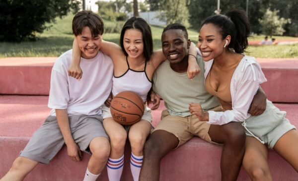 group of kids hugging one with a basketball