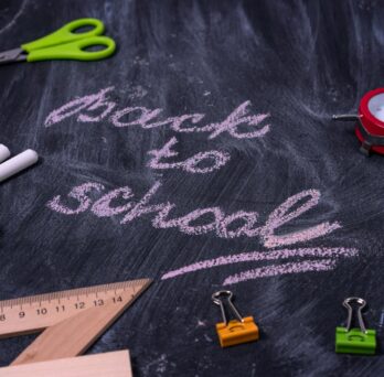 chalk board with back to school written and scissors chalk and binder clips
                  